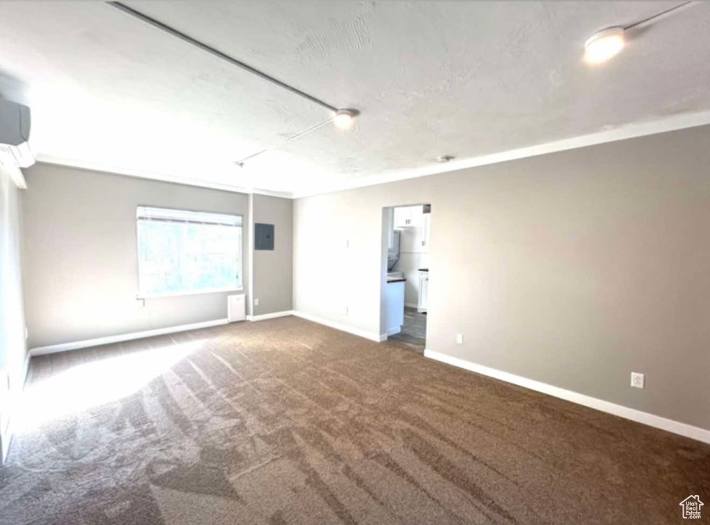 Unfurnished room with attic access, dark colored carpet, electric panel, and baseboards