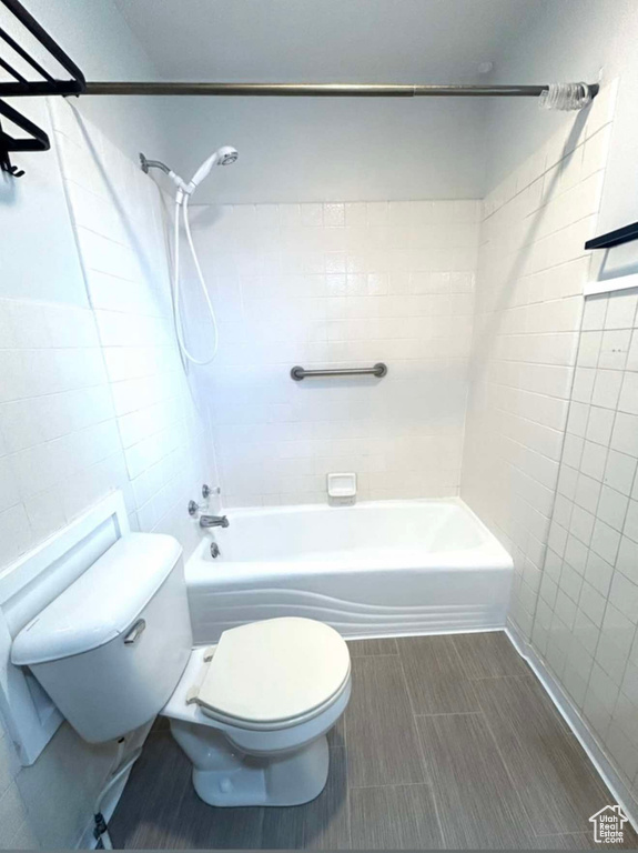 Full bathroom with toilet, shower / tub combination, and tile walls