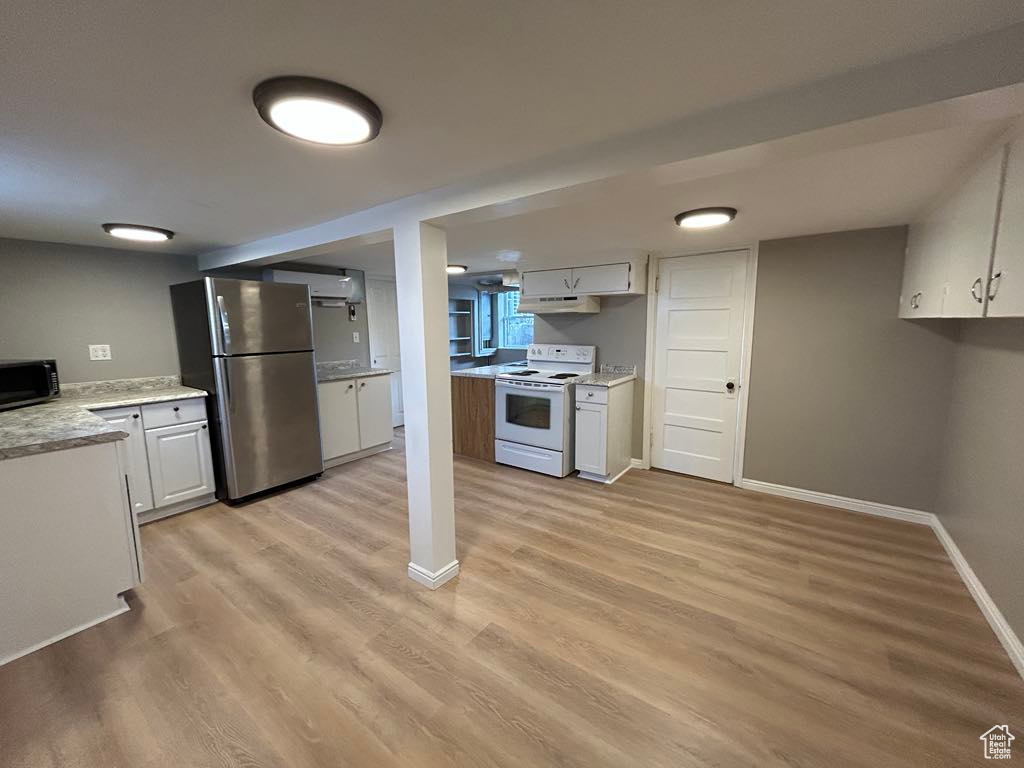 Kitchen featuring light wood-style flooring, white cabinets, stainless steel appliances, and baseboards