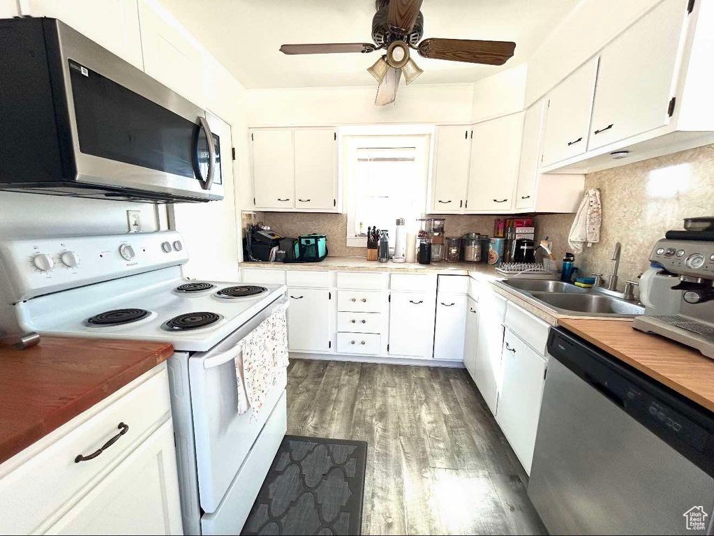 Kitchen featuring appliances with stainless steel finishes, light wood-style floors, white cabinets, and tasteful backsplash