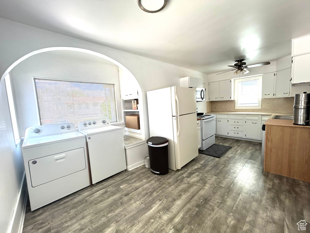 Kitchen featuring dark wood-style flooring, white appliances, washer and dryer, ceiling fan, and white cabinets