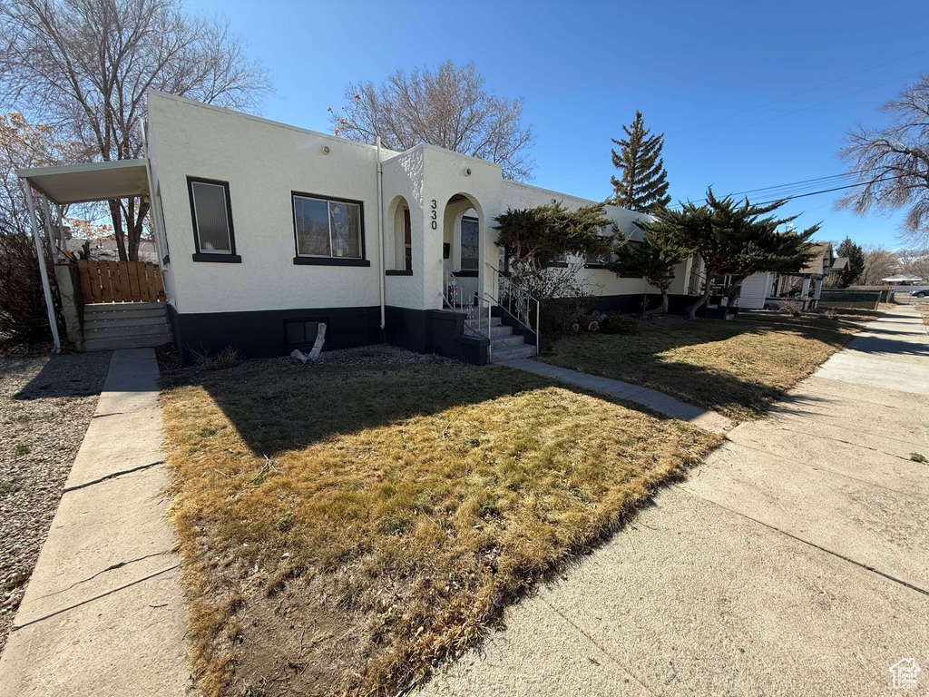 View of front of house with a front lawn and stucco siding