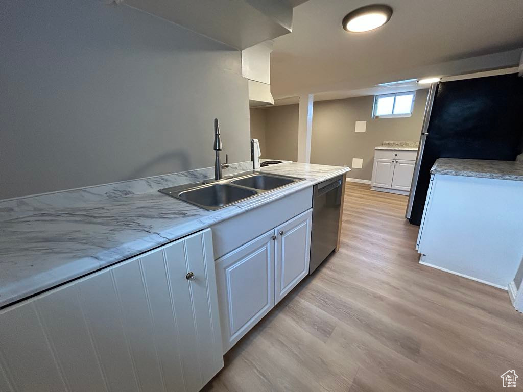 Kitchen featuring light wood-style flooring, a sink, white cabinetry, appliances with stainless steel finishes, and light countertops