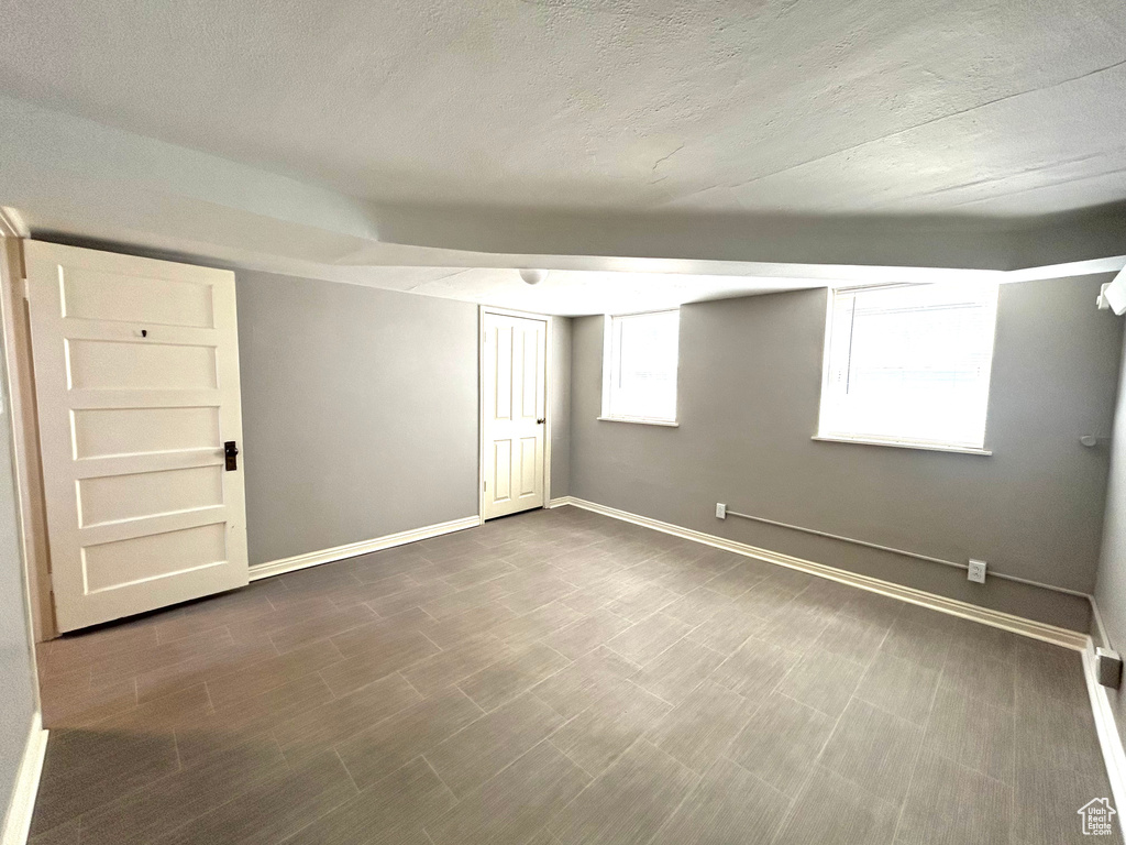 Basement featuring a textured ceiling and baseboards