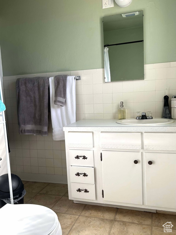 Bathroom featuring tile walls, tile patterned flooring, and vanity