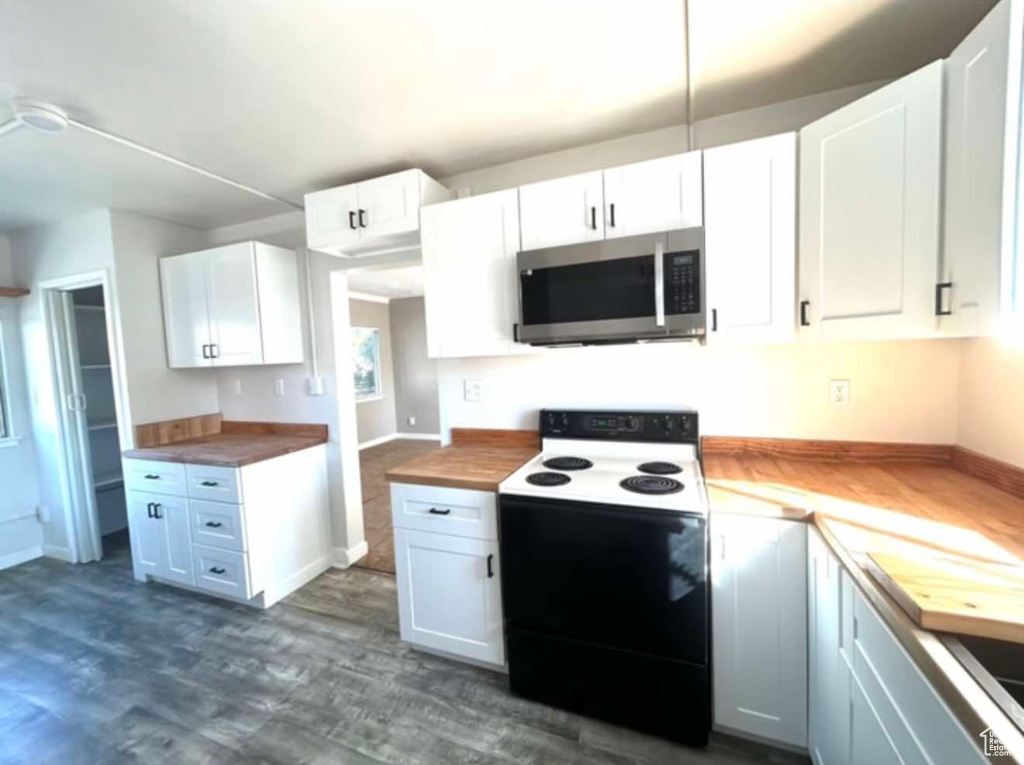 Kitchen featuring electric stove, stainless steel microwave, and white cabinetry