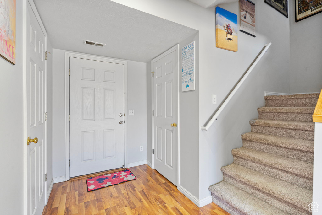 Entrance foyer with stairs, wood finished floors, visible vents, and baseboards