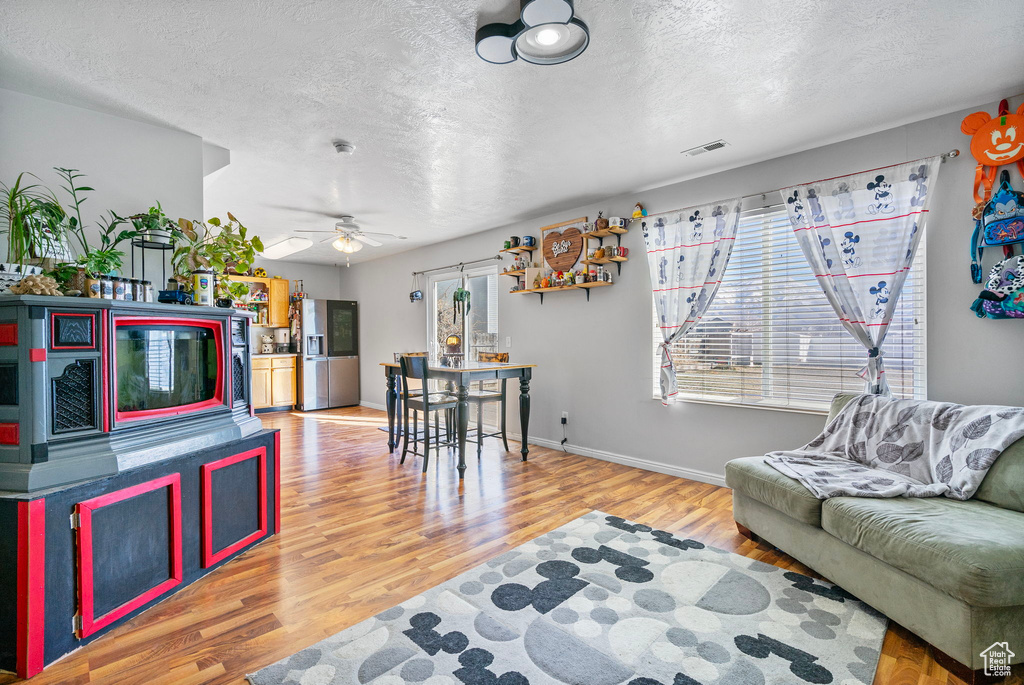 Living area featuring a textured ceiling, visible vents, and wood finished floors