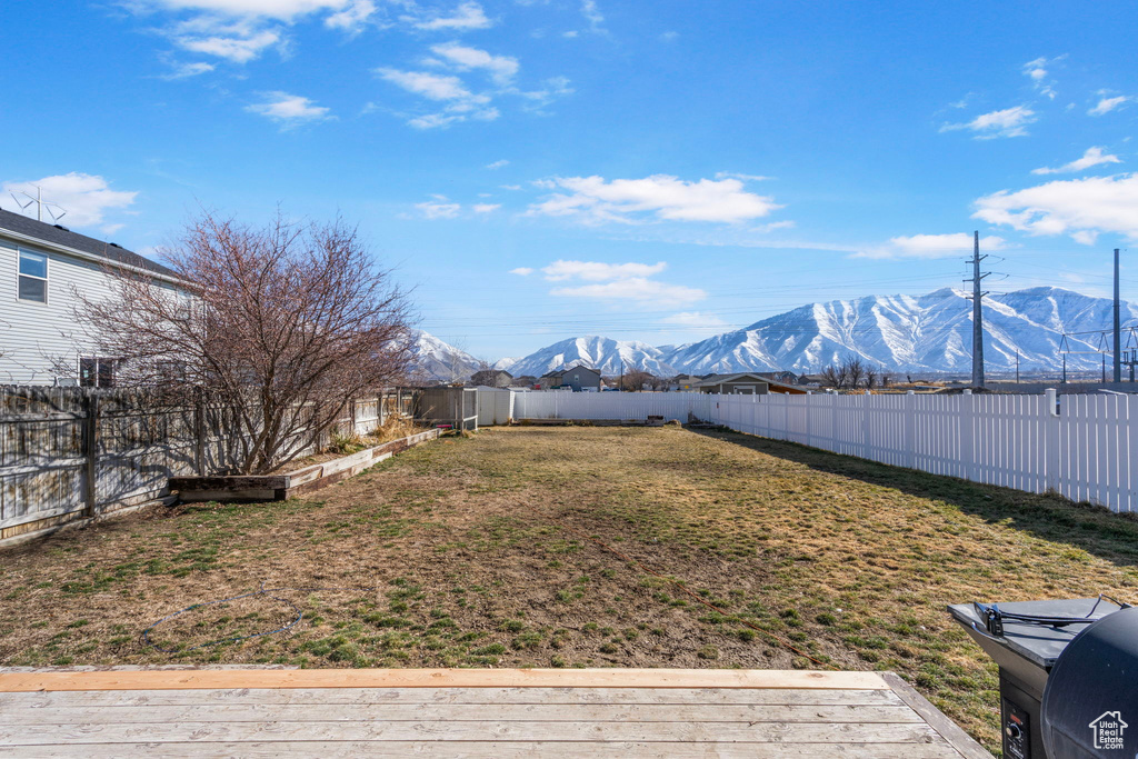 View of yard with a deck with mountain view and a fenced backyard