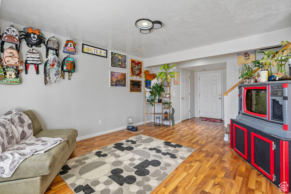 Living area with a textured ceiling, baseboards, and wood finished floors