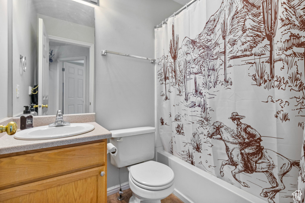 Bathroom featuring toilet, shower / bathtub combination with curtain, and vanity