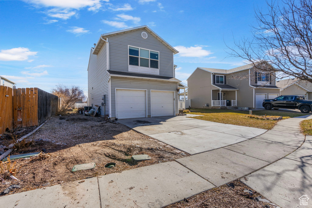 Traditional-style house featuring an attached garage, fence, and concrete driveway