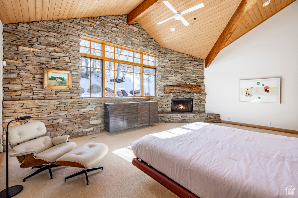 Carpeted bedroom featuring high vaulted ceiling, wood ceiling with exposed beams, and a stone fireplace