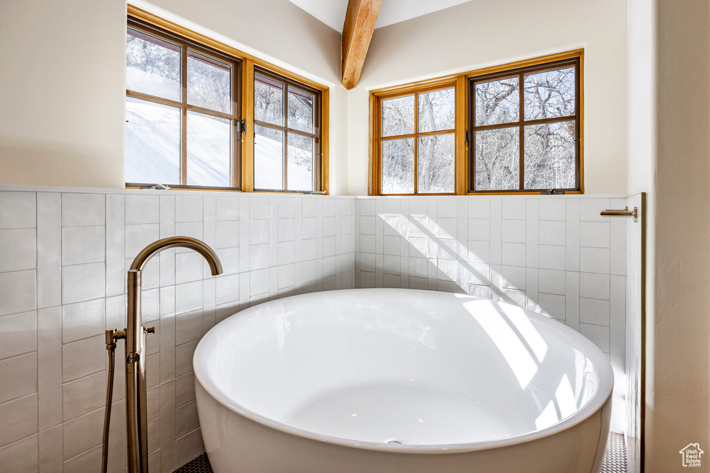 Full bathroom featuring tile walls, a freestanding bath, healthy amount of natural light, and wainscoting