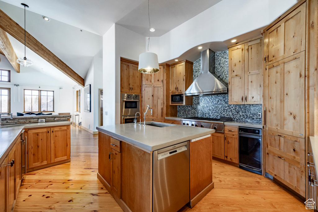 Kitchen with wall chimney exhaust hood, a sink, stainless steel appliances, light wood finished floors, and recessed lighting