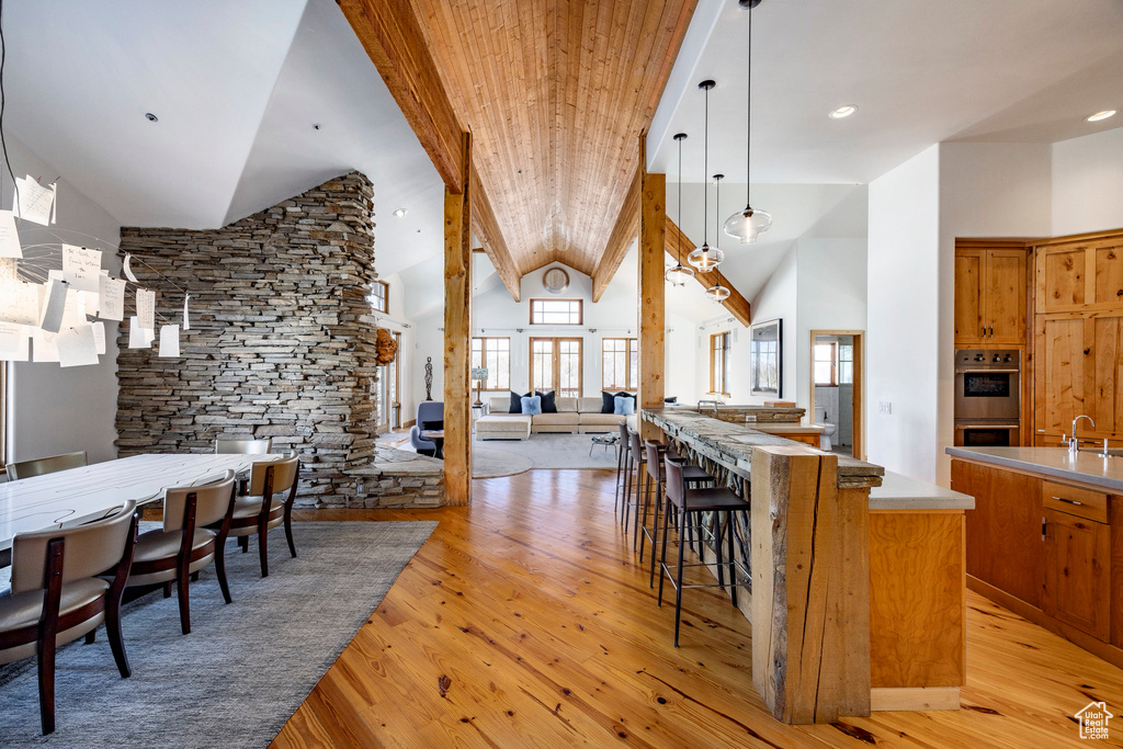 Kitchen with double oven, open floor plan, brown cabinets, light wood-style floors, and high vaulted ceiling