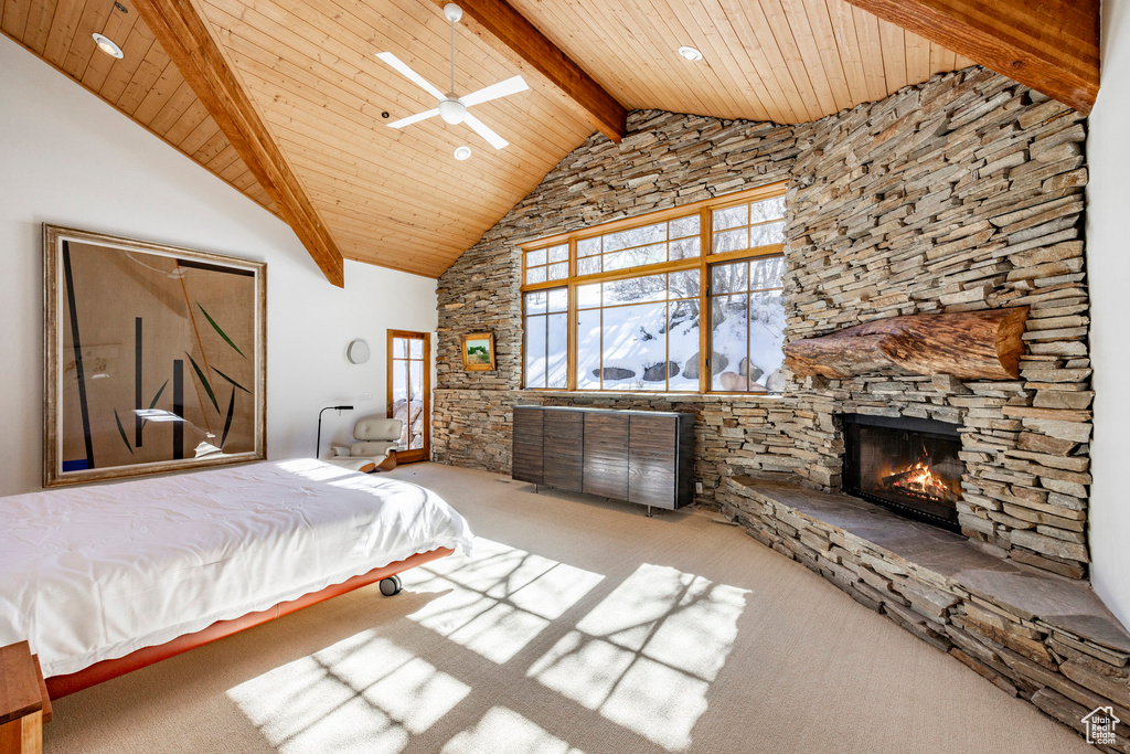 Carpeted bedroom with wooden ceiling with exposed beams, a stone fireplace, and high vaulted ceiling