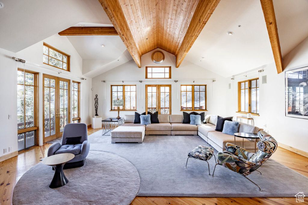 Living room with french doors, wood finished floors, high vaulted ceiling, and beam ceiling