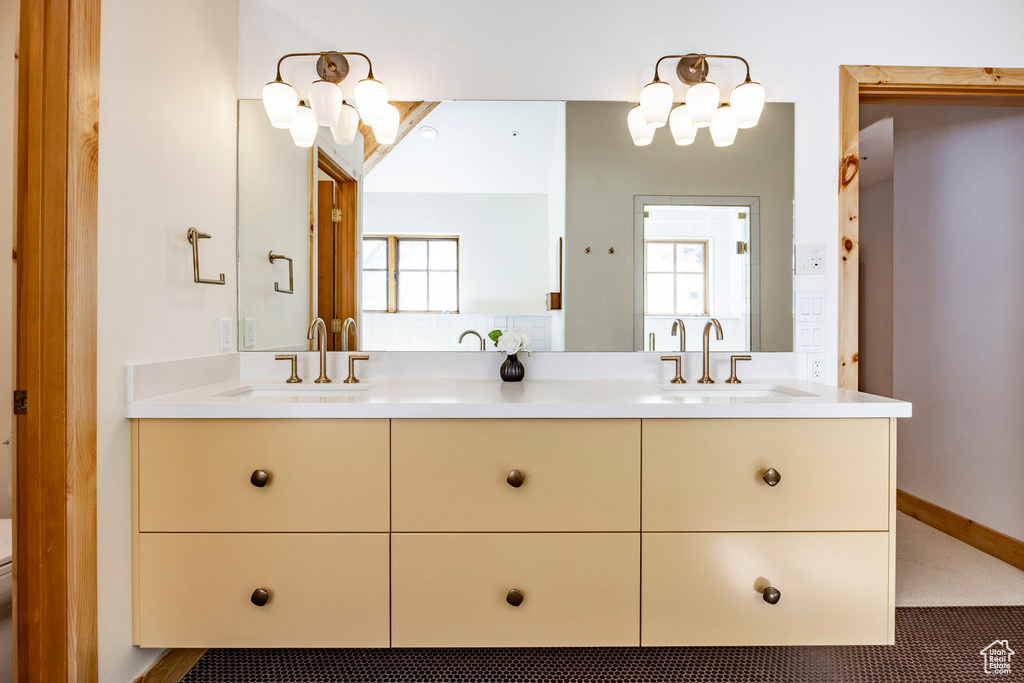Bathroom with double vanity, a chandelier, plenty of natural light, and toilet