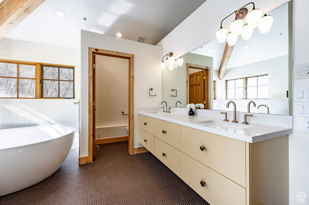 Full bathroom with a freestanding bath, double vanity, toilet, and recessed lighting