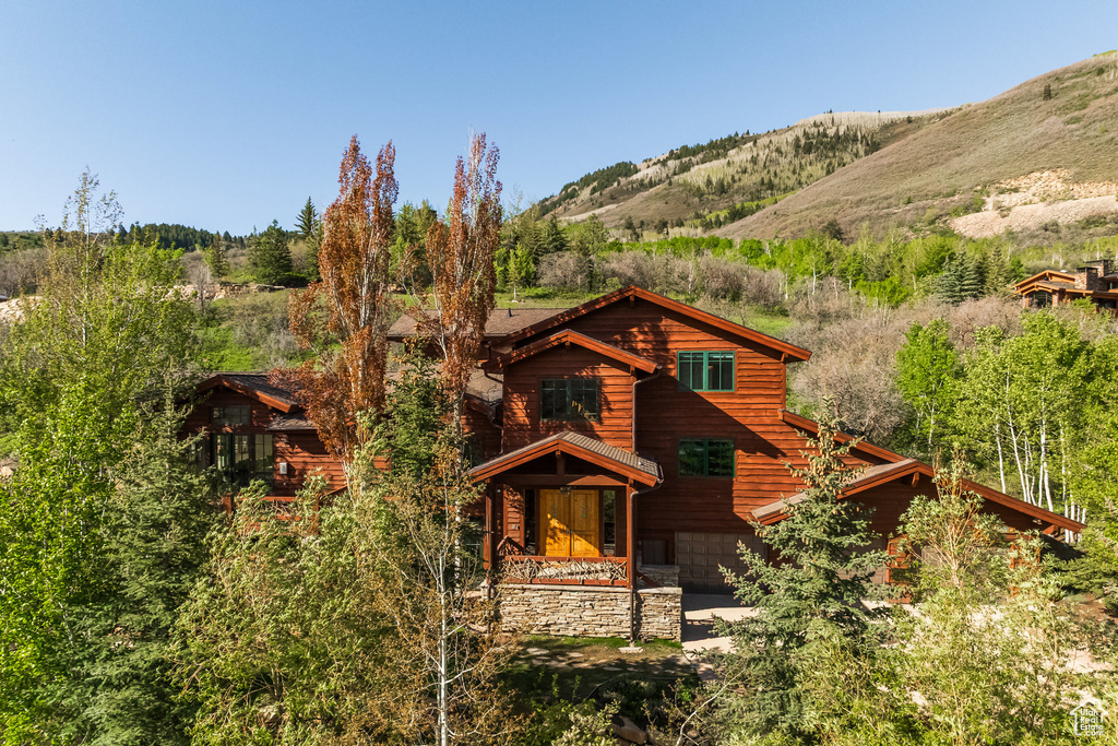 View of front facade with a garage, a mountain view, and stone siding