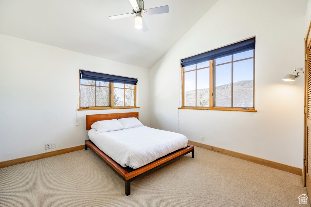 Carpeted bedroom with baseboards, lofted ceiling, and ceiling fan