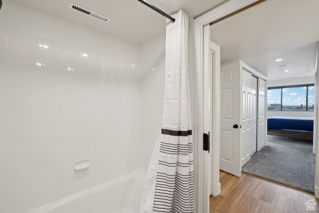 Bathroom featuring visible vents, shower / bathtub combination with curtain, ensuite bath, and wood finished floors