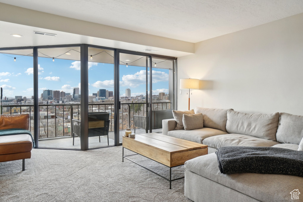 Carpeted living area featuring a wall of windows, a view of city, and visible vents