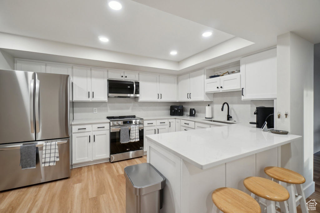 Kitchen featuring a sink, appliances with stainless steel finishes, white cabinets, and light countertops