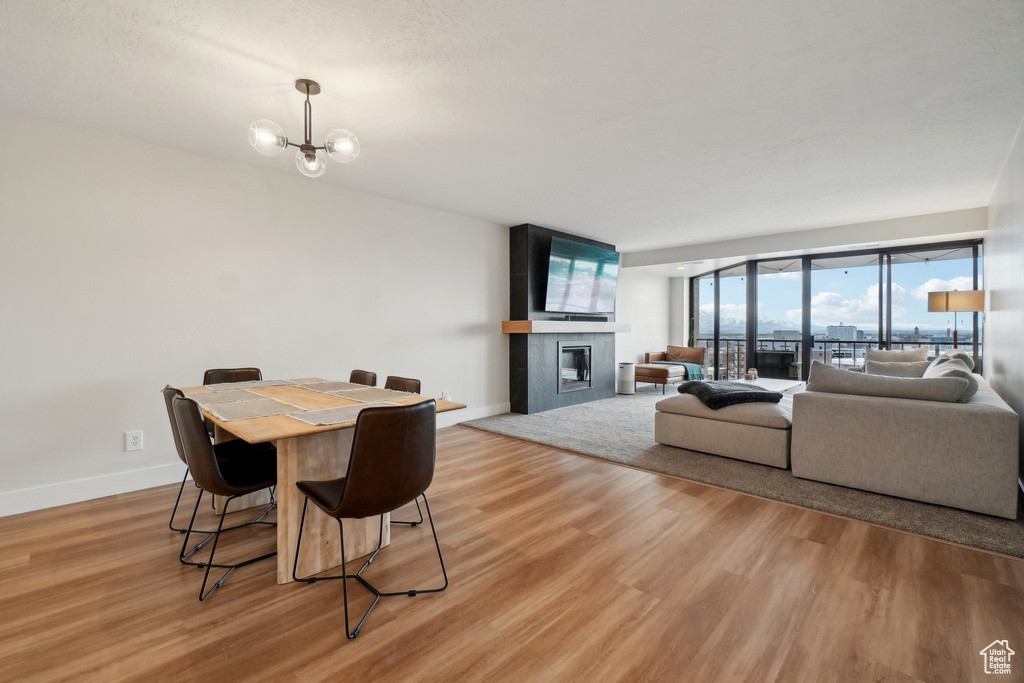 Dining area with light wood-type flooring, a fireplace, baseboards, and an inviting chandelier