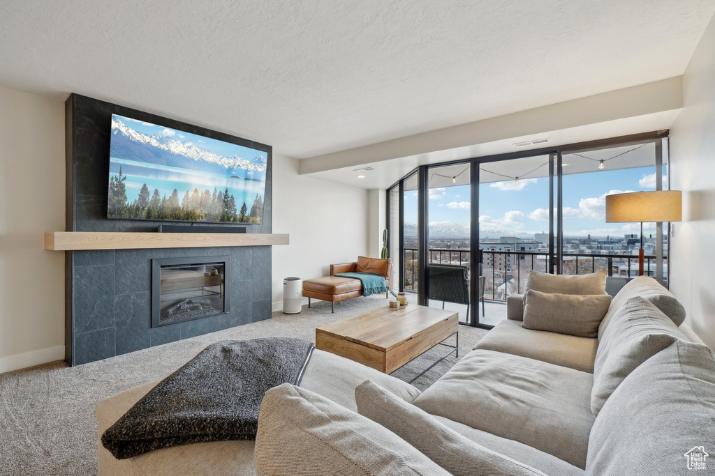 Living room with a textured ceiling, carpet floors, a tile fireplace, and baseboards