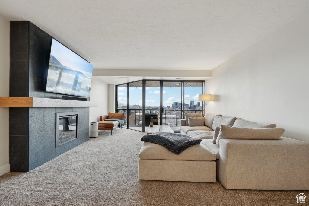 Living area with a wall of windows, carpet flooring, a fireplace, and a textured ceiling