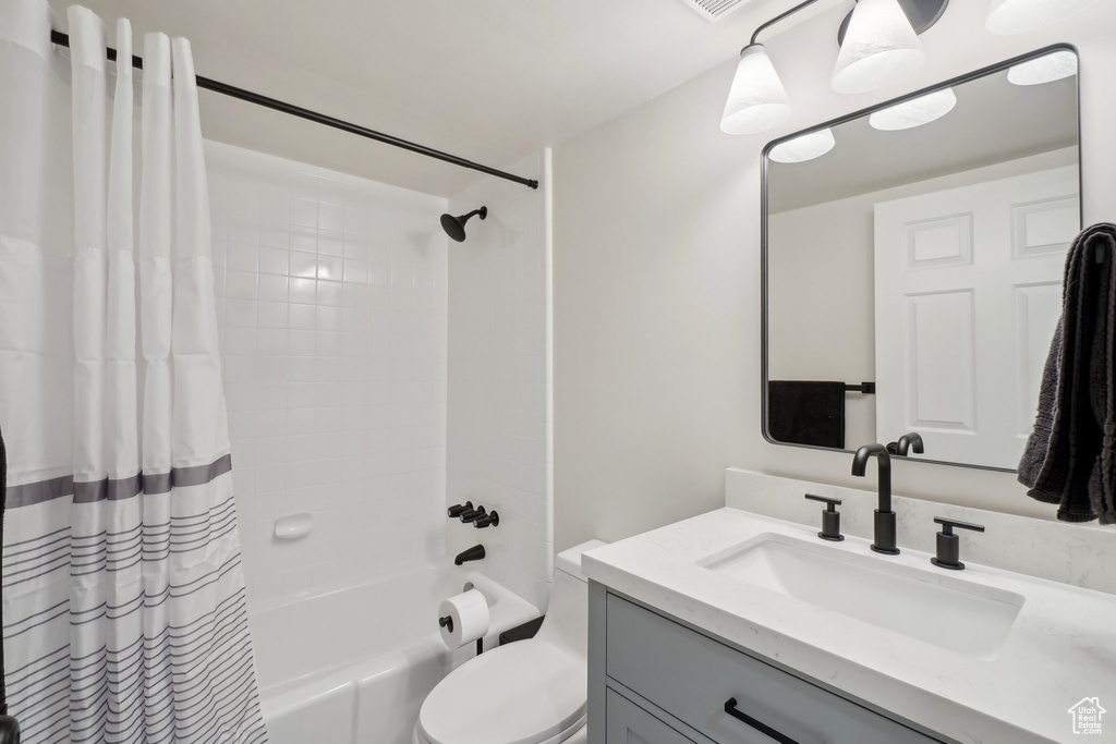 Full bath with vanity, toilet, and shower / bath combo with shower curtain