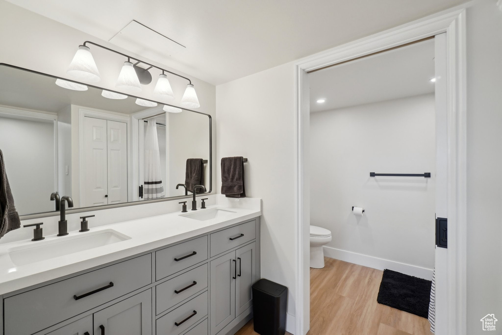 Bathroom featuring double vanity, toilet, a sink, and wood finished floors