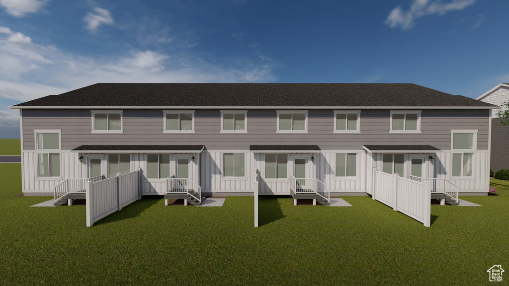 Rear view of property with board and batten siding, a lawn, and a shingled roof