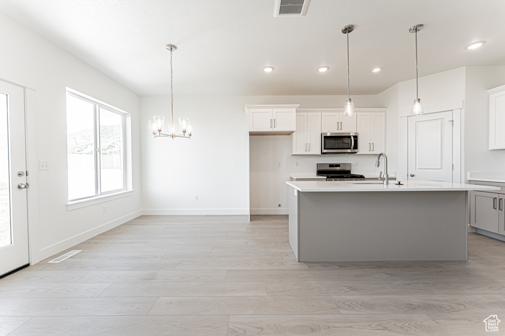 Kitchen with stainless steel appliances, light countertops, recessed lighting, light wood-style flooring, and a sink