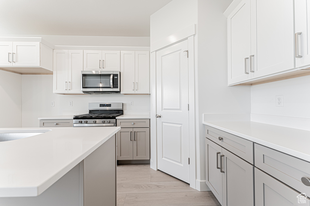 Kitchen featuring appliances with stainless steel finishes, light countertops, light marble finish floors, and white cabinets
