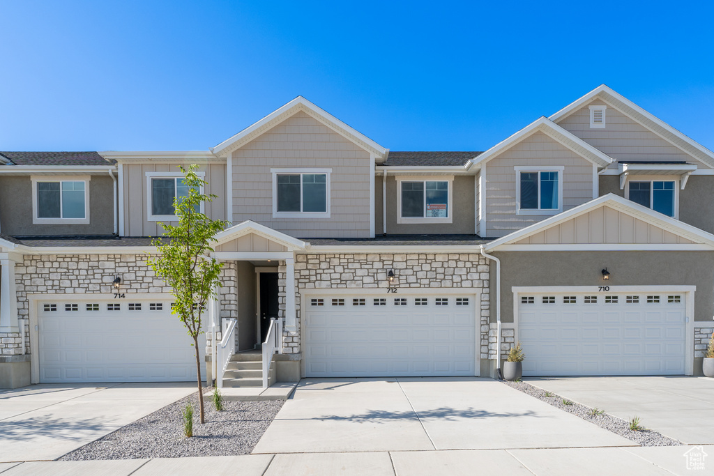View of property featuring a garage, concrete driveway, and stone siding