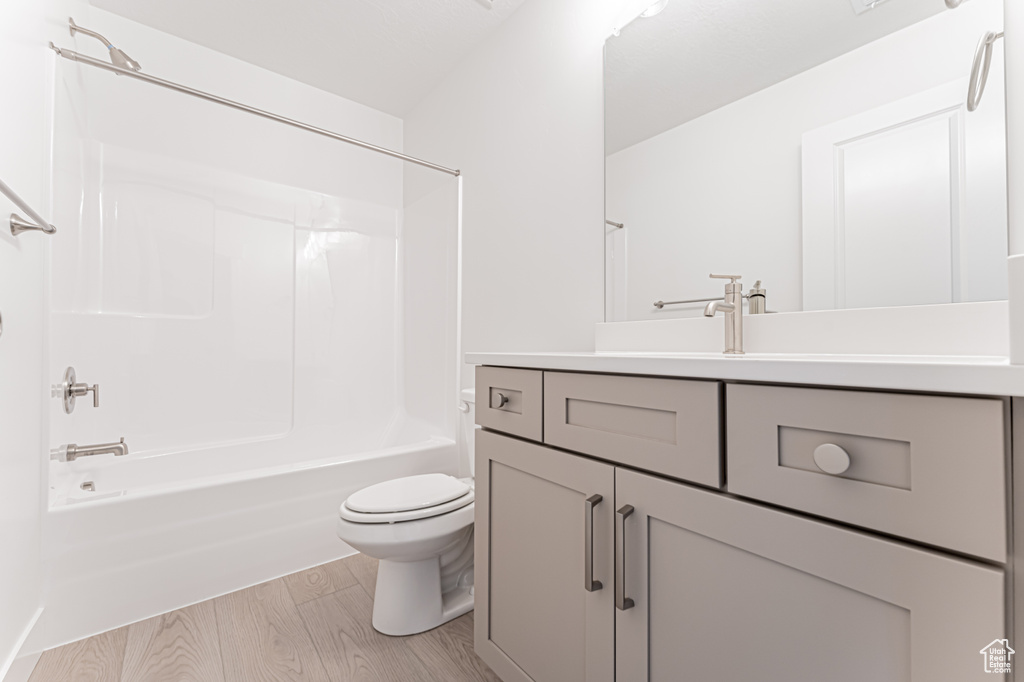 Bathroom featuring toilet, vanity, wood finished floors, and shower / bath combination