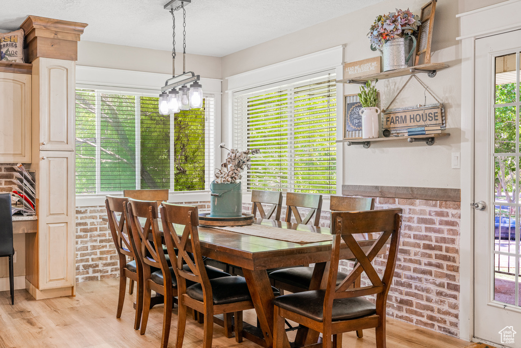 Dining room featuring light wood-type flooring and brick wall