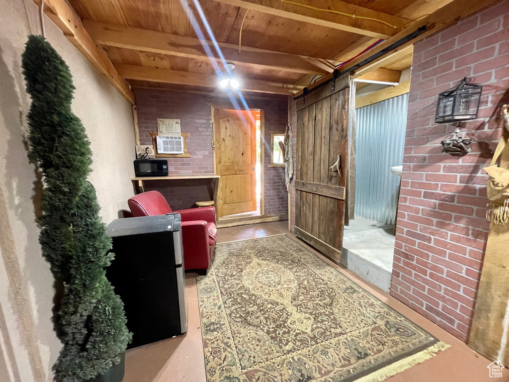 Interior space featuring finished concrete flooring, brick wall, wooden ceiling, and beam ceiling