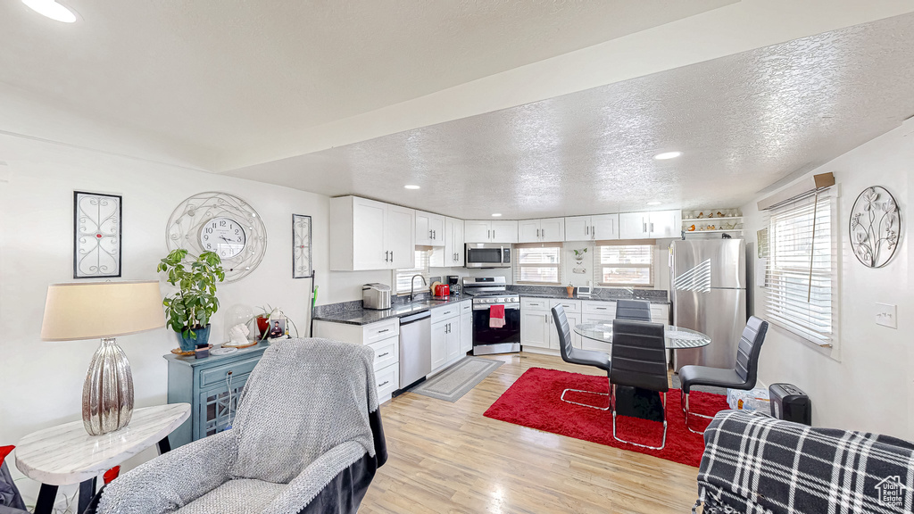 Kitchen featuring appliances with stainless steel finishes, sink, white cabinets, light hardwood / wood-style floors, and a textured ceiling