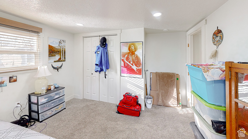 Bedroom featuring light colored carpet, a closet, and a textured ceiling