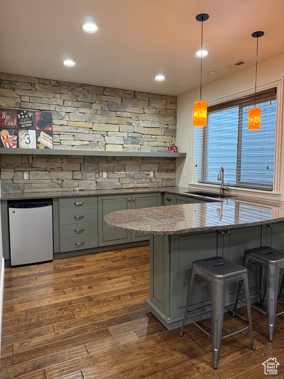 Bar with dark wood-type flooring, pendant lighting, a sink, and fridge