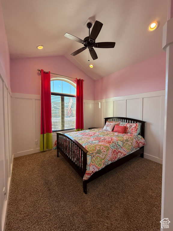 Bedroom featuring a ceiling fan, dark colored carpet, a wainscoted wall, and vaulted ceiling