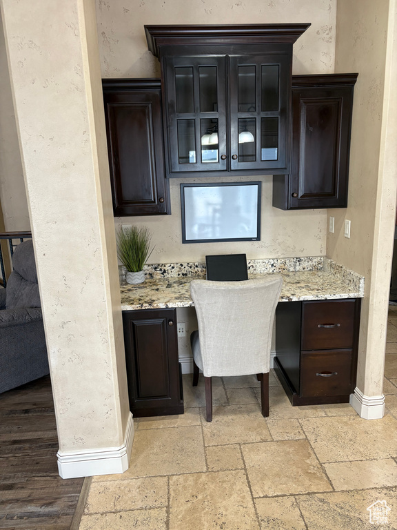 Interior space featuring stone tile flooring, built in study area, and baseboards