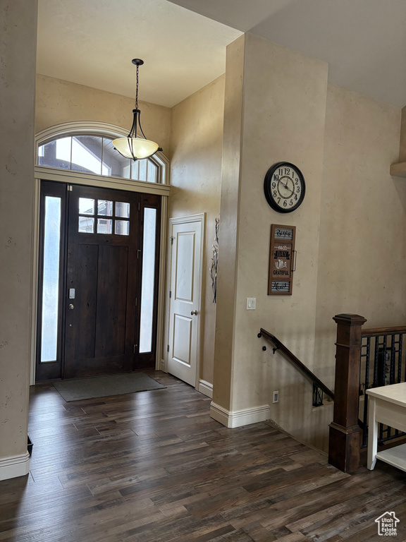 Entrance foyer with dark wood-style floors, a towering ceiling, and baseboards