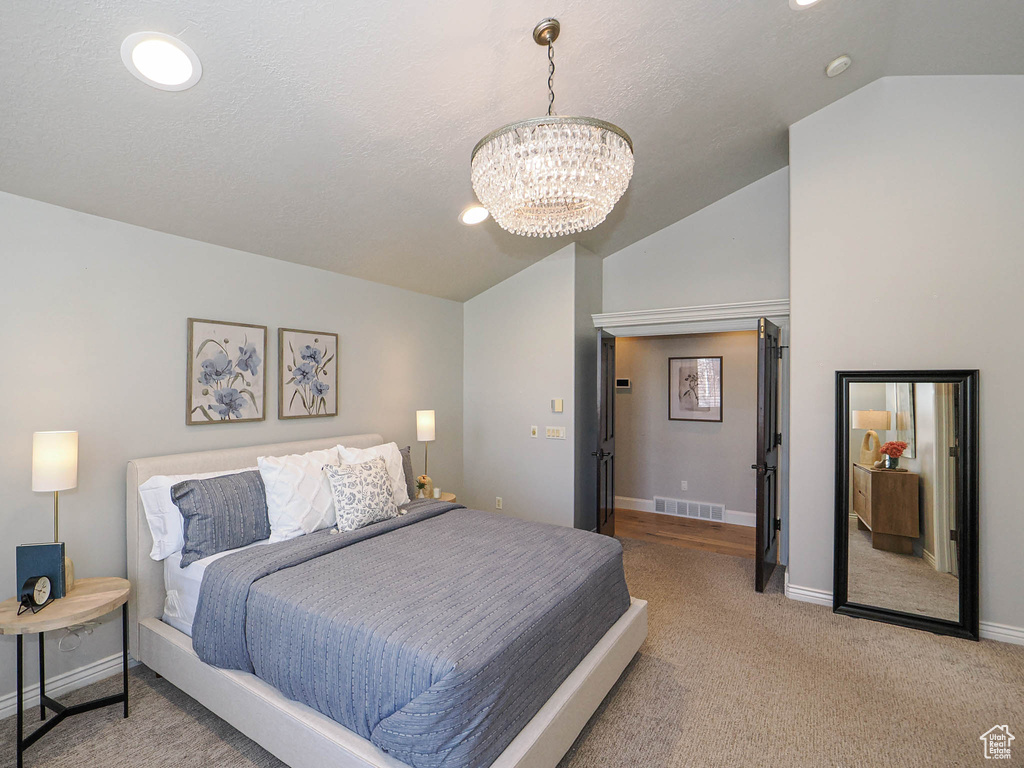 Bedroom with light carpet, baseboards, visible vents, an inviting chandelier, and vaulted ceiling
