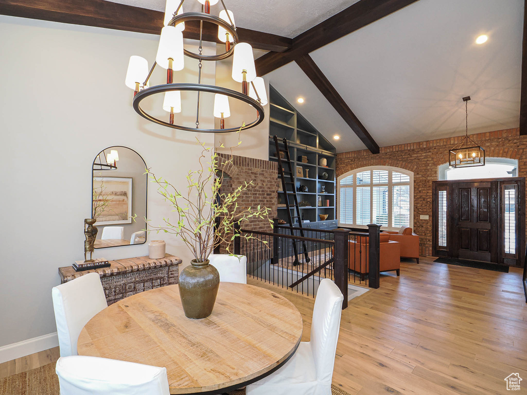 Dining area featuring built in shelves, a notable chandelier, brick wall, and wood finished floors