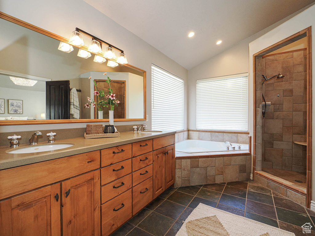 Bathroom featuring a garden tub, double vanity, a sink, and lofted ceiling